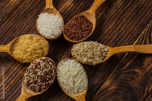 Wooden spoons with different rice types on the wooden background