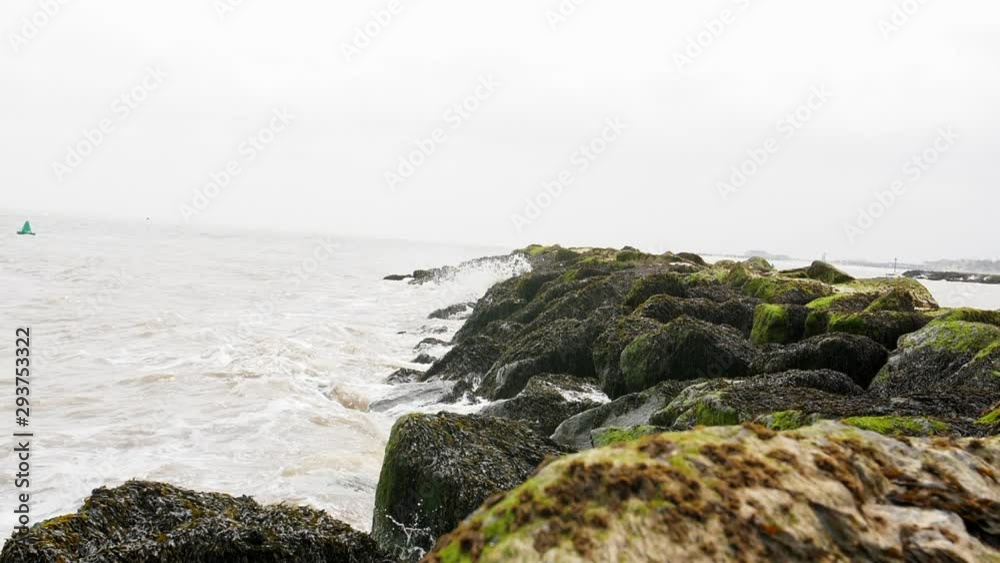 4K Waves crashing against Rocks on a British Beach by the sea, Natural Coast Line with a fishing boat on water waves and rugged shore with moss and grassy boulders. 4K Waves crashing against Rocks on a British Beach by the sea, Natural Coast Line with a fishing boat on water waves and rugged shore with moss and grassy boulders.