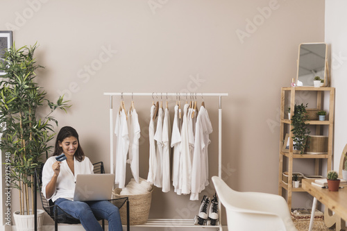 Woman holding a credit card and working on laptop © Freepik