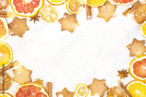 Border of Dried slices of various citrus fruits gingerbread and spices on white background with copyspace