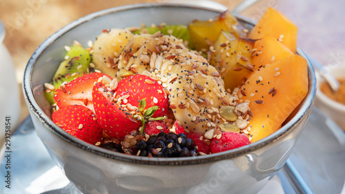 Delicious and healthy breakfast option, granola and fruit bowl featuring strawberries, bananas, kiwis, starfruit and papaya, oats, nutritious nuts and seeds, served with milk or yogurt and brown sugar