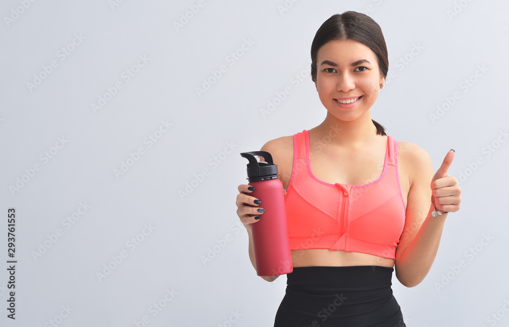Attractive happy young fit sportswoman standing isolated over gray background Attractive happy young fit sportswoman standing isolated over gray background
