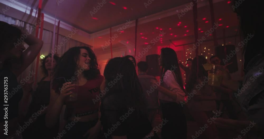 Big home party lots of young ladies and guys dancing and chilling out in a large spacious living room