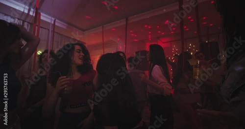 Big home party lots of young ladies and guys dancing and chilling out in a large spacious living room