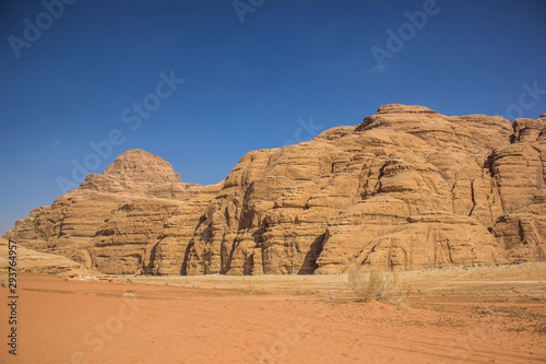 planet Earth world heritage touristic destination site Wadi Rum Jordan Middle East scenery landscape view sand valley foreground and picturesque mountain ridge on blue sky background 