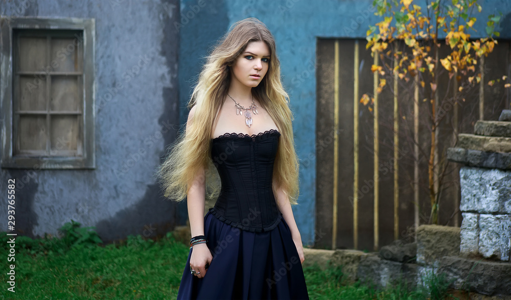 Young beautiful mysterious girl in black dress in old medieval town