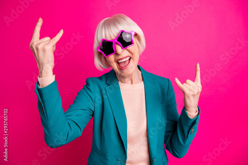 Photo of screaming white haired shouting rocking mature woman wearing beige sweater green jacket star shaped pink spectacles isolated over maroon vivid color background