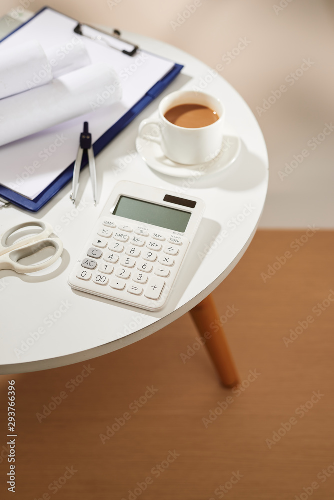 Top view of coffee notebook empty page, calculator, scissors on white table Top view of coffee notebook empty page, calculator, scissors on white table