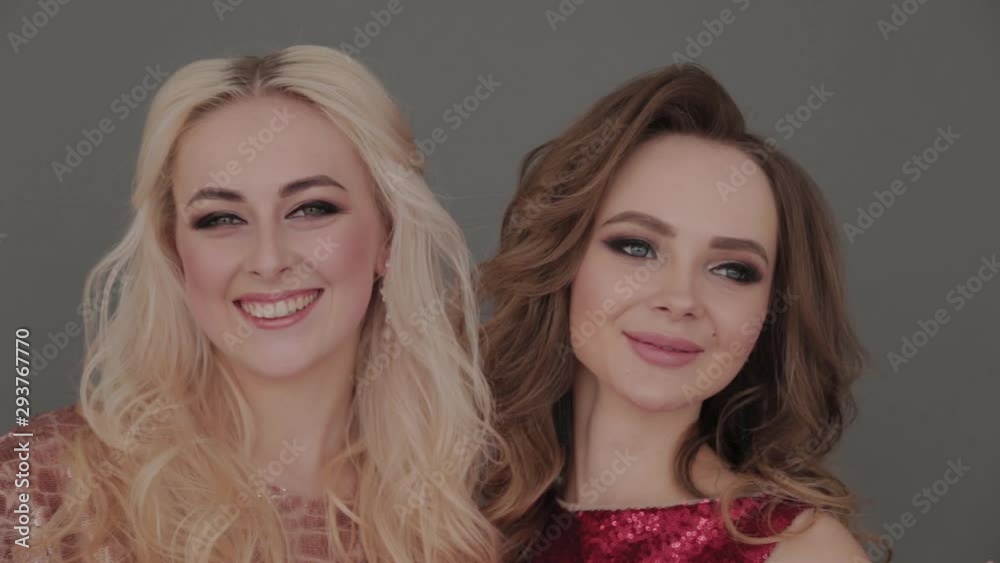 Two young and beautiful girls on a gray background with glasses of champagne in hands. Two young and beautiful girls on a gray background with glasses of champagne in hands.