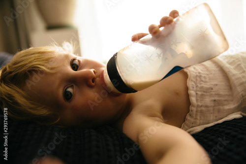 Kleiner Junge trinkt Milch aus einer Flasche photo