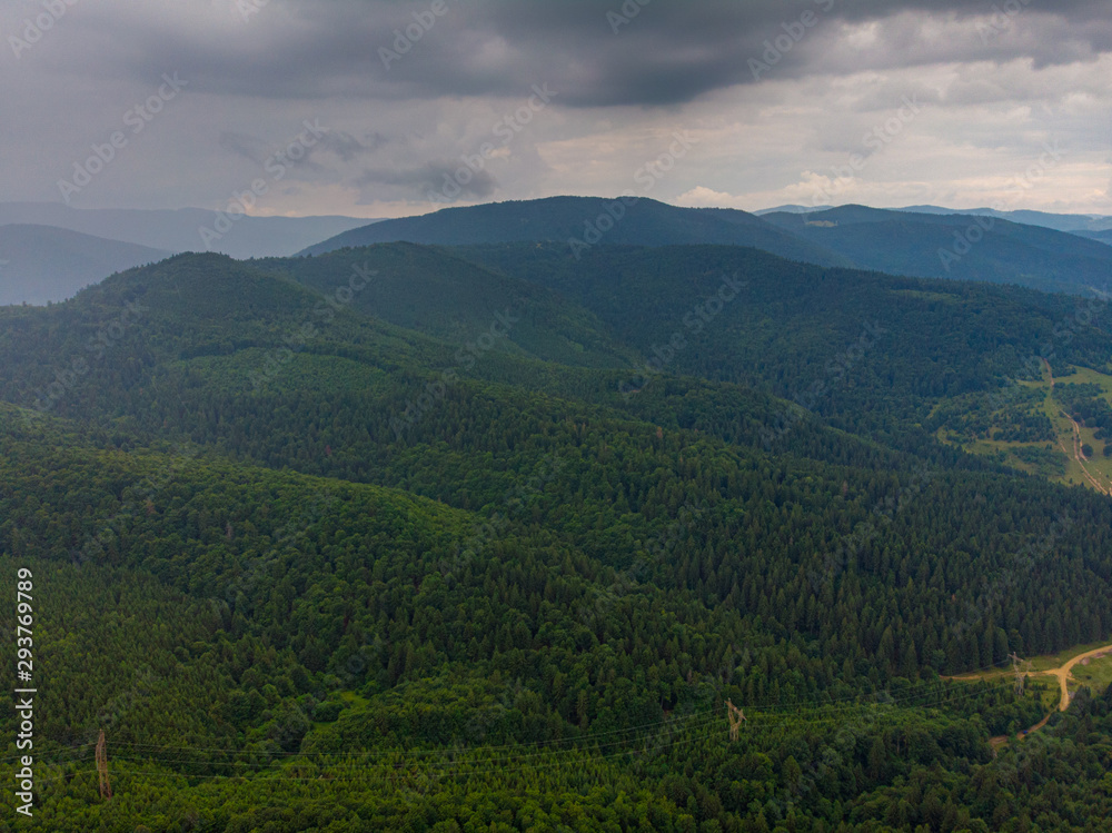 Fototapeta premium Aerial view over mountain road going through forest landscape. Transylvania, Romania