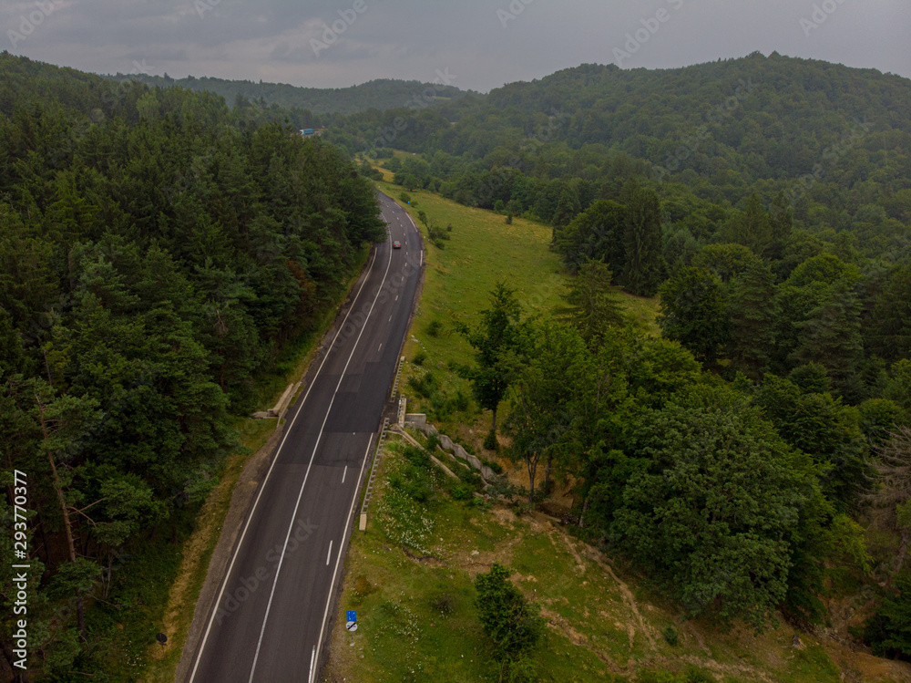 Aerial view over mountain road going through forest landscape. Transylvania, Romania