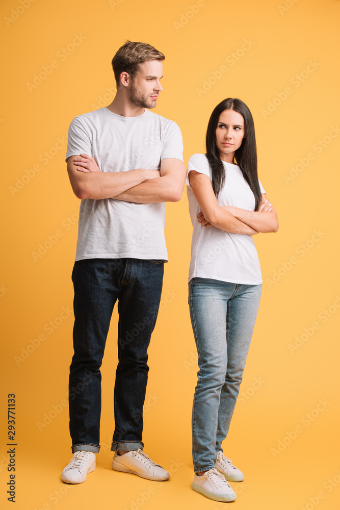 offended couple in bad mood standing with crossed arms on yellow offended couple in bad mood standing with crossed arms on yellow