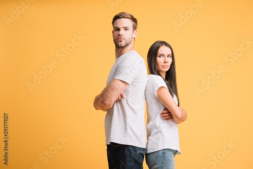 offended couple standing with crossed arms, isolated on yellow © LIGHTFIELD STUDIOS