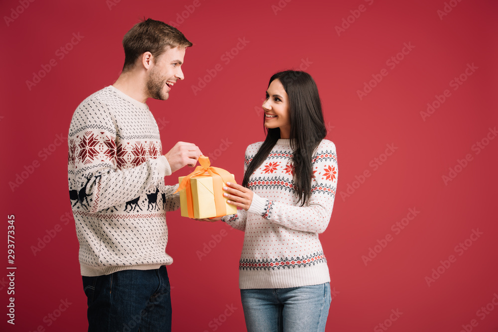 happy couple with christmas present isolated on red