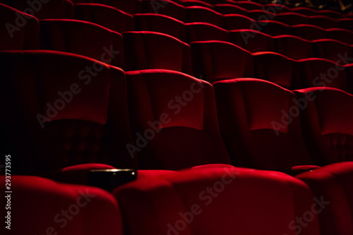 empty red velvet seats in cinema auditorium .