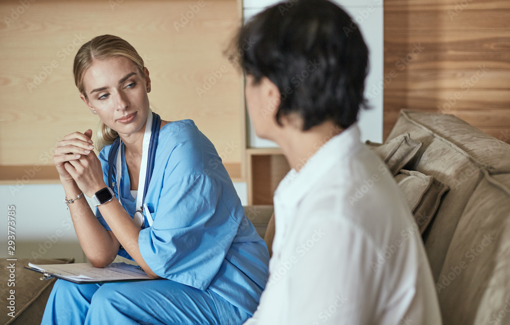 Obraz premium Friendly smiling doctor and patient sitting on the couch. Very good news and high level medical care concept.