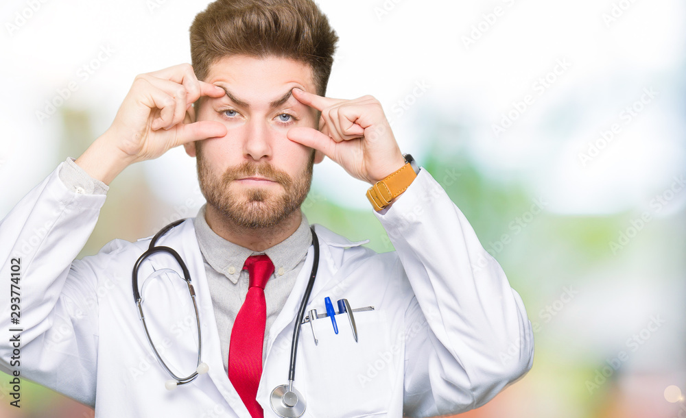 Young handsome doctor man wearing medical coat Trying to open eyes with fingers, sleepy and tired for morning fatigue Young handsome doctor man wearing medical coat Trying to open eyes with fingers, sleepy and tired for morning fatigue