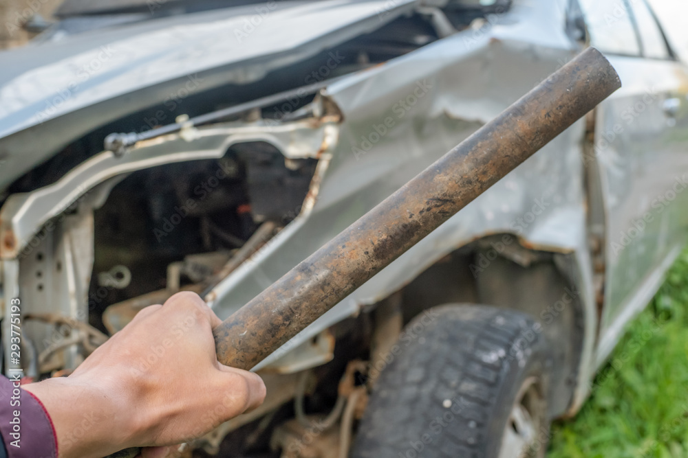 Hand with a metal bat on the background of the car. Aggression towards drivers Hand with a metal bat on the background of the car. Aggression towards drivers
