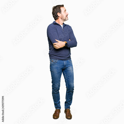 Middle age handsome man wearing a sweater smiling looking to the side with arms crossed convinced and confident