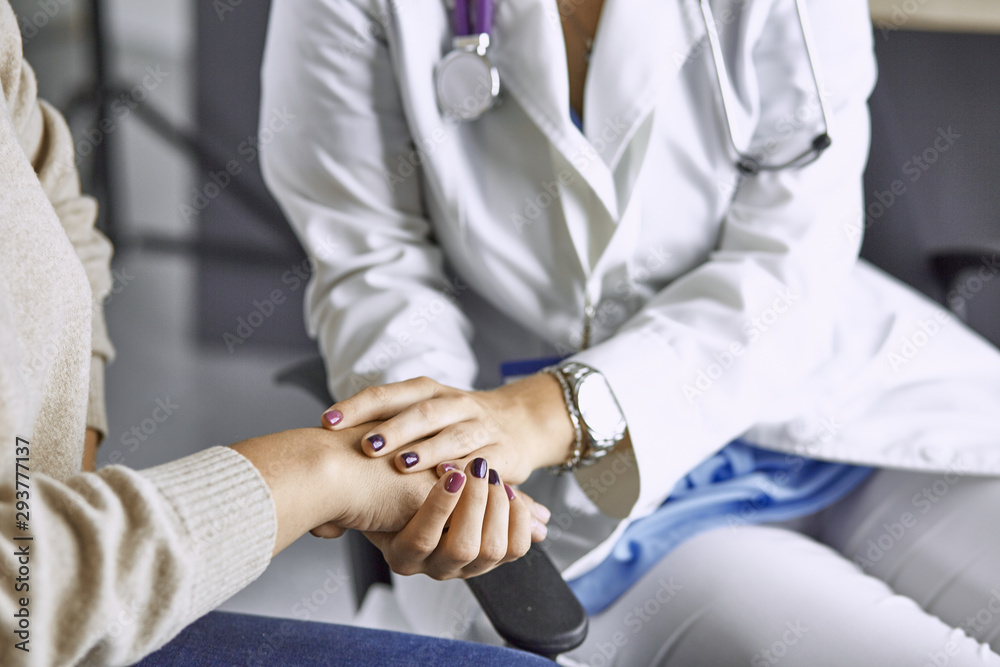 Woman doctor calms patient and holds hand