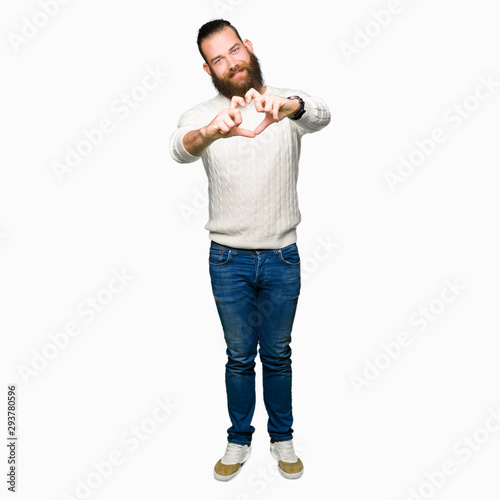 Young hipster man wearing winter sweater smiling in love showing heart symbol and shape with hands. Romantic concept.