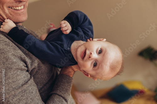 Baby wird von einem Mann gehalten und streckt den Nacken durch photo