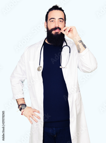 Doctor with long hair wearing medical coat and stethoscope mouth and lips shut as zip with fingers. Secret and silent, taboo talking