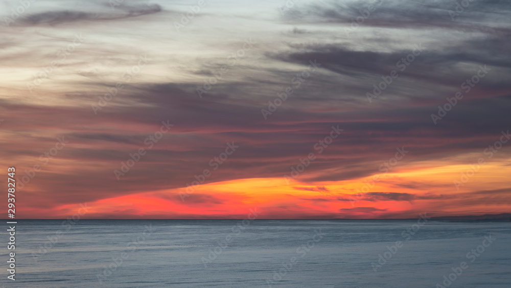 Beautiful Summer landscape sunset image of colorful vibrant sky over calm long exposure sea