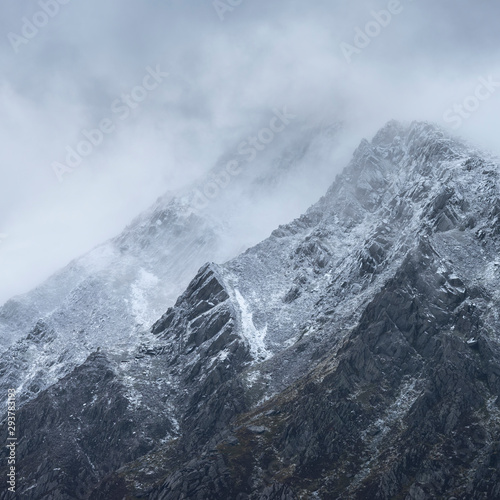 Stunning detail landscape images of snowcapped Pen Yr Ole Wen mountain in Snowdonia during dramatic moody Winter storm © veneratio
