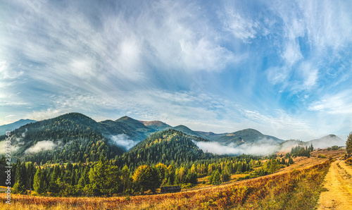 Aerial view amazing over of the Carpathian Mountains or Carpathians with Beautiful autumn landscape , sunrise, blue sky with white clouds, fog between the mountain slopes