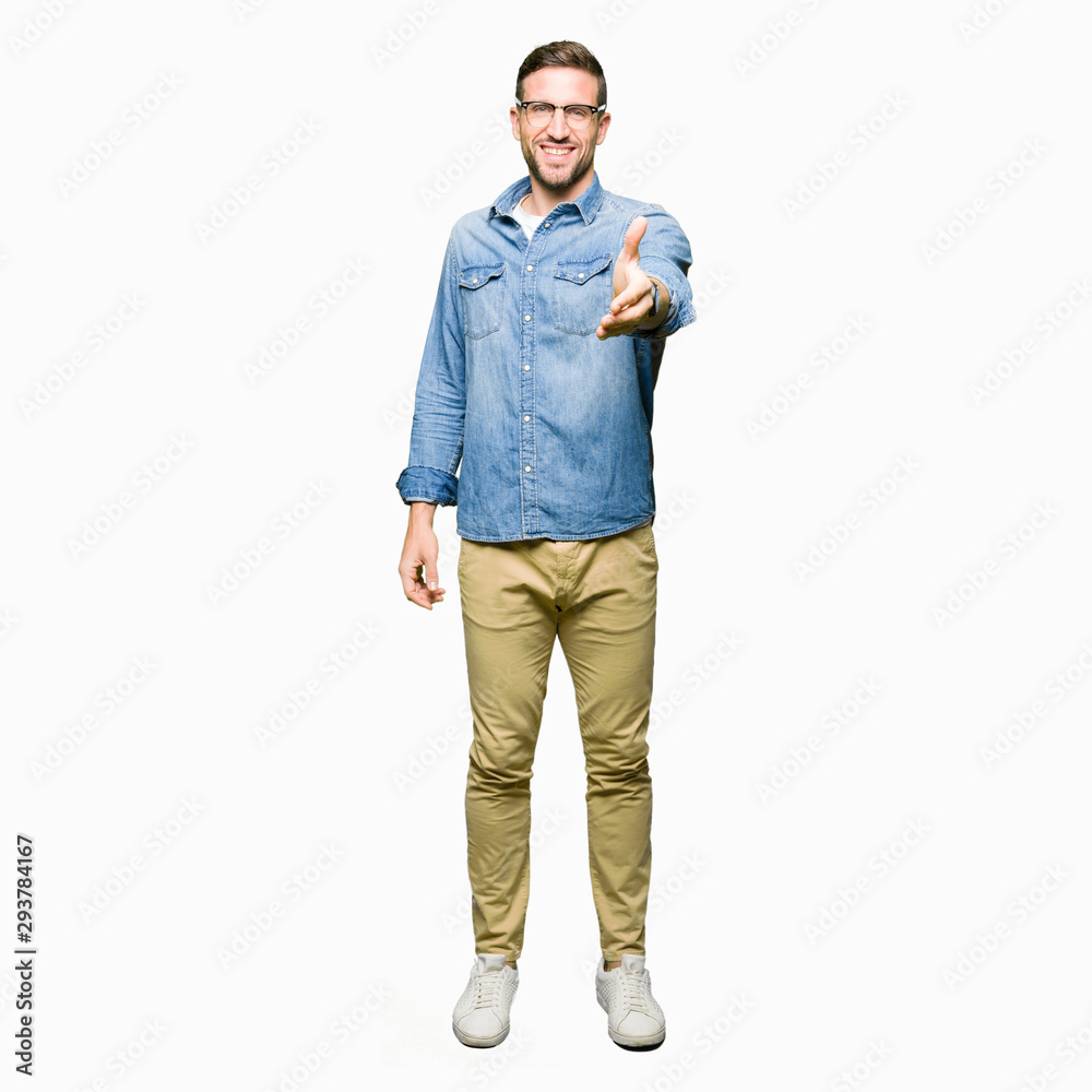 Fototapeta premium Handsome man wearing glasses smiling friendly offering handshake as greeting and welcoming. Successful business.