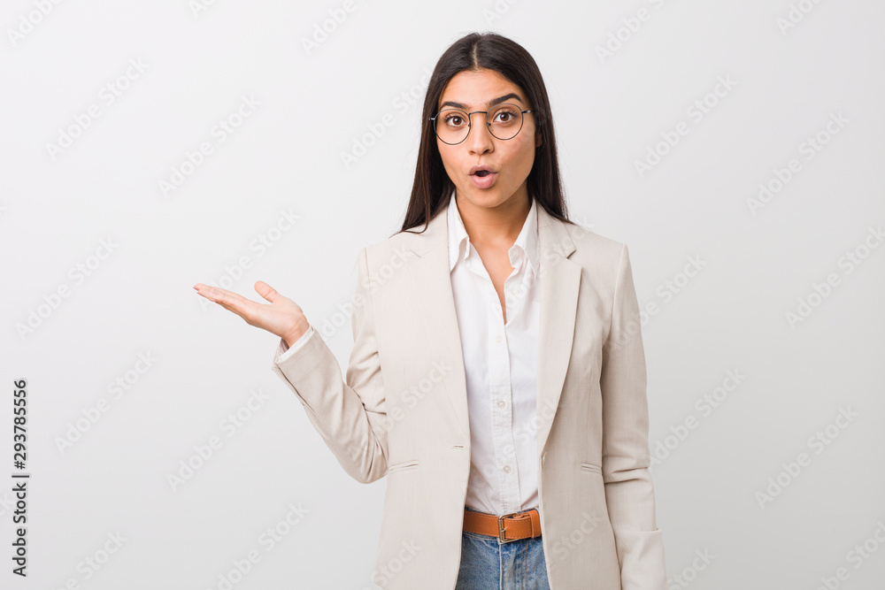 Young business arab woman isolated against a white background impressed holding copy space on palm. Young business arab woman isolated against a white background impressed holding copy space on palm.