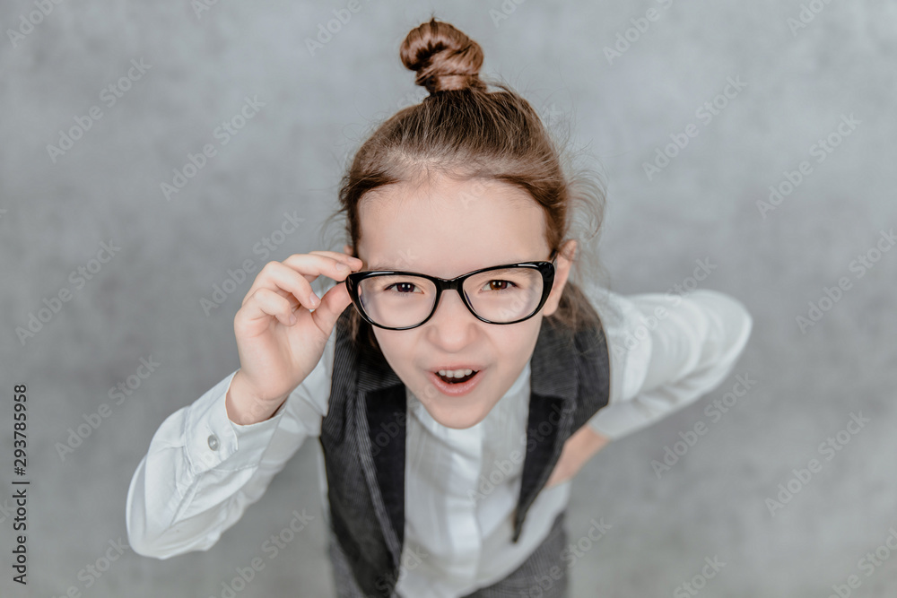 Close-up of a small business lady on a gray background. Dressed in glasses. Holding their hand is a business wand. Going to the camera. Close-up of a small business lady on a gray background. Dressed in glasses. Holding their hand is a business wand. Going to the camera.