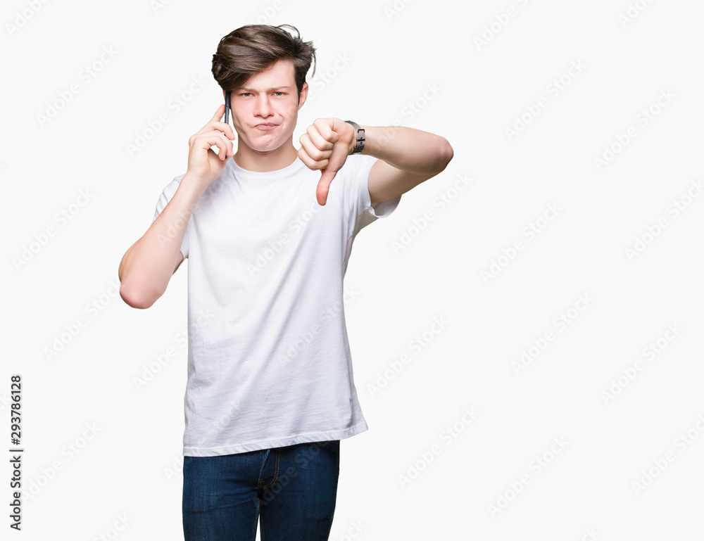 Young man talking on smartphone over isolated background with angry face, negative sign showing dislike with thumbs down, rejection concept Young man talking on smartphone over isolated background with angry face, negative sign showing dislike with thumbs down, rejection concept