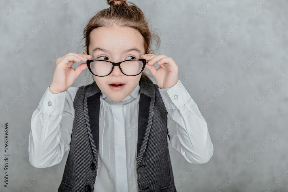 Isolated on a gray background a little business lady. During this close-up is wearing glasses. Isolated on a gray background a little business lady. During this close-up is wearing glasses.