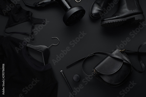 Black monochromatic flatlay on black background. Clothes, accessories and beauty equipment. Black friday sale concept. Copy space