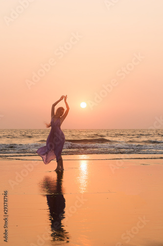 Young slim beautiful woman dancing on sunset beach, bohemian outfit, indie style, summer vacation, sunny, romantic, splashing water, silhouette, happy