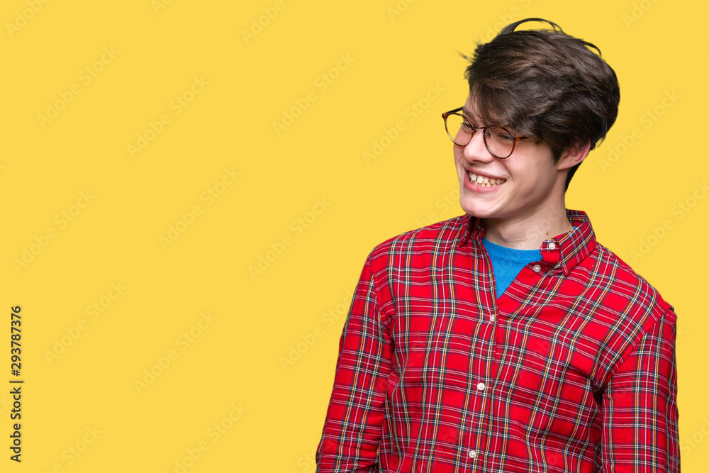 Young handsome man wearing glasses over isolated background looking away to side with smile on face, natural expression. Laughing confident.