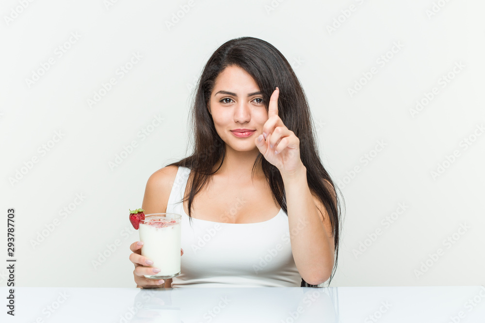 Young hispanic woman holding a smoothie young hispanic woman holding an avocado toast showing number one with finger.< mixto >