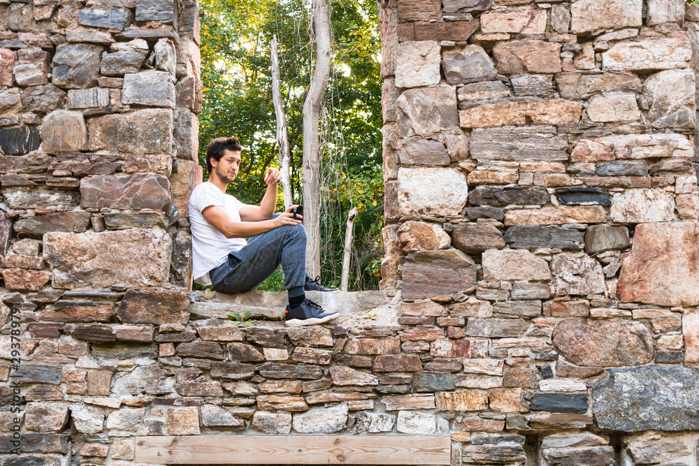 young man relaxing with coffee outdoors in window of abandoned building