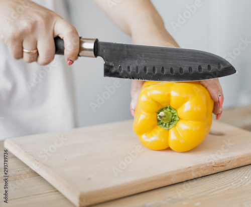 Pregnant woman cutting a yellow pepper