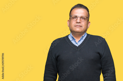 Middle age bussines arab man wearing glasses over isolated background with serious expression on face. Simple and natural looking at the camera.