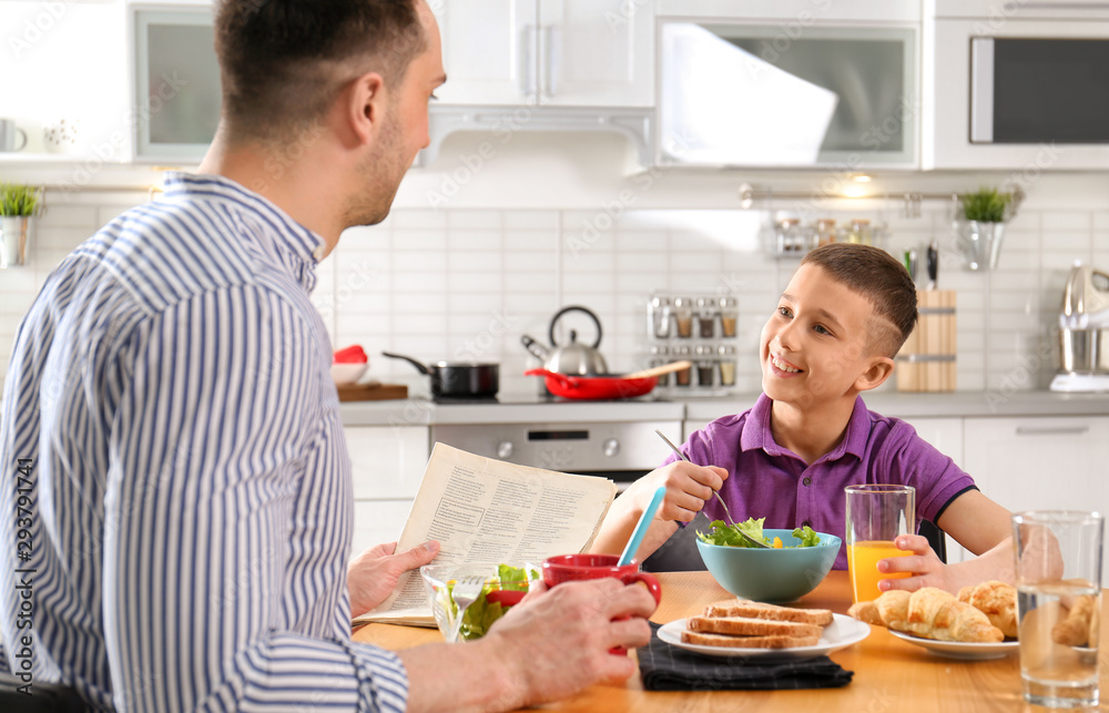 Dad and son having breakfast together in kitchen Dad and son having breakfast together in kitchen