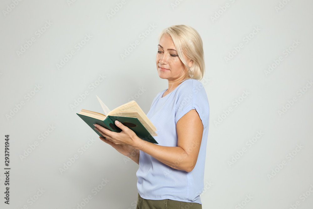 Mature woman reading book on light background Mature woman reading book on light background