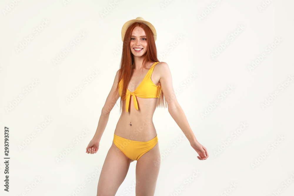 beautiful young woman with red hair in a swimsuit on a white background