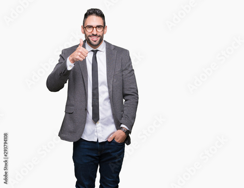 Young handsome business man over isolated background doing happy thumbs up gesture with hand. Approving expression looking at the camera showing success. © Krakenimages.com