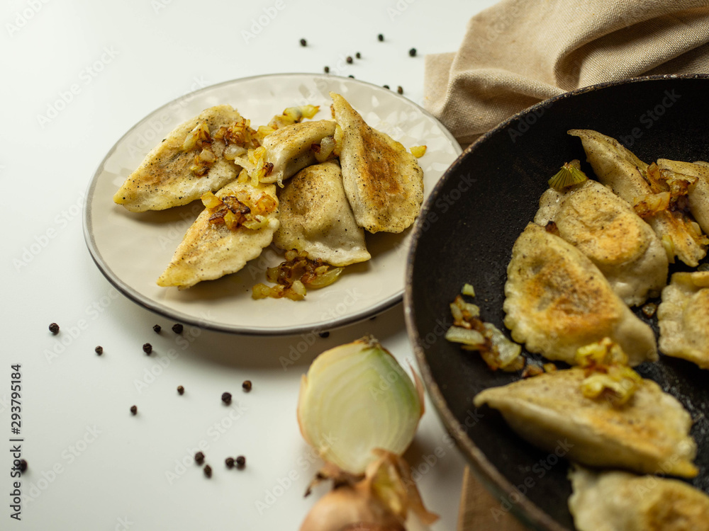 Domowe pierogi z mięsem i smażoną cebulką. Jasne tło. Domowe pierogi z mięsem i smażoną cebulką. Jasne tło.