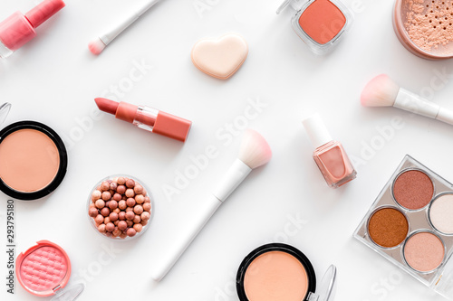 Makeup set with powder, rouge and brusheson white background top view pattern