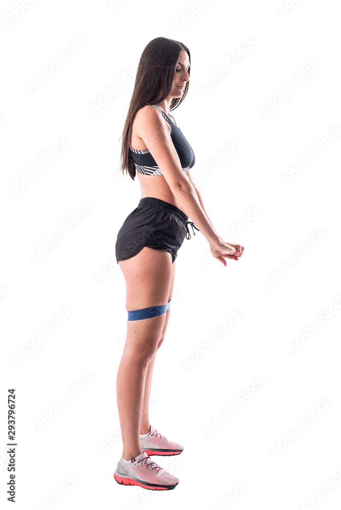 Side view of slim fitness girl doing squat exercises resistance bands on legs. Standing position. Full body isolated on white background. Side view of slim fitness girl doing squat exercises resistance bands on legs. Standing position. Full body isolated on white background.